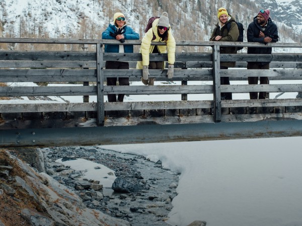 Four friends in a snowy landscape enjoying the view from a wooden bridge