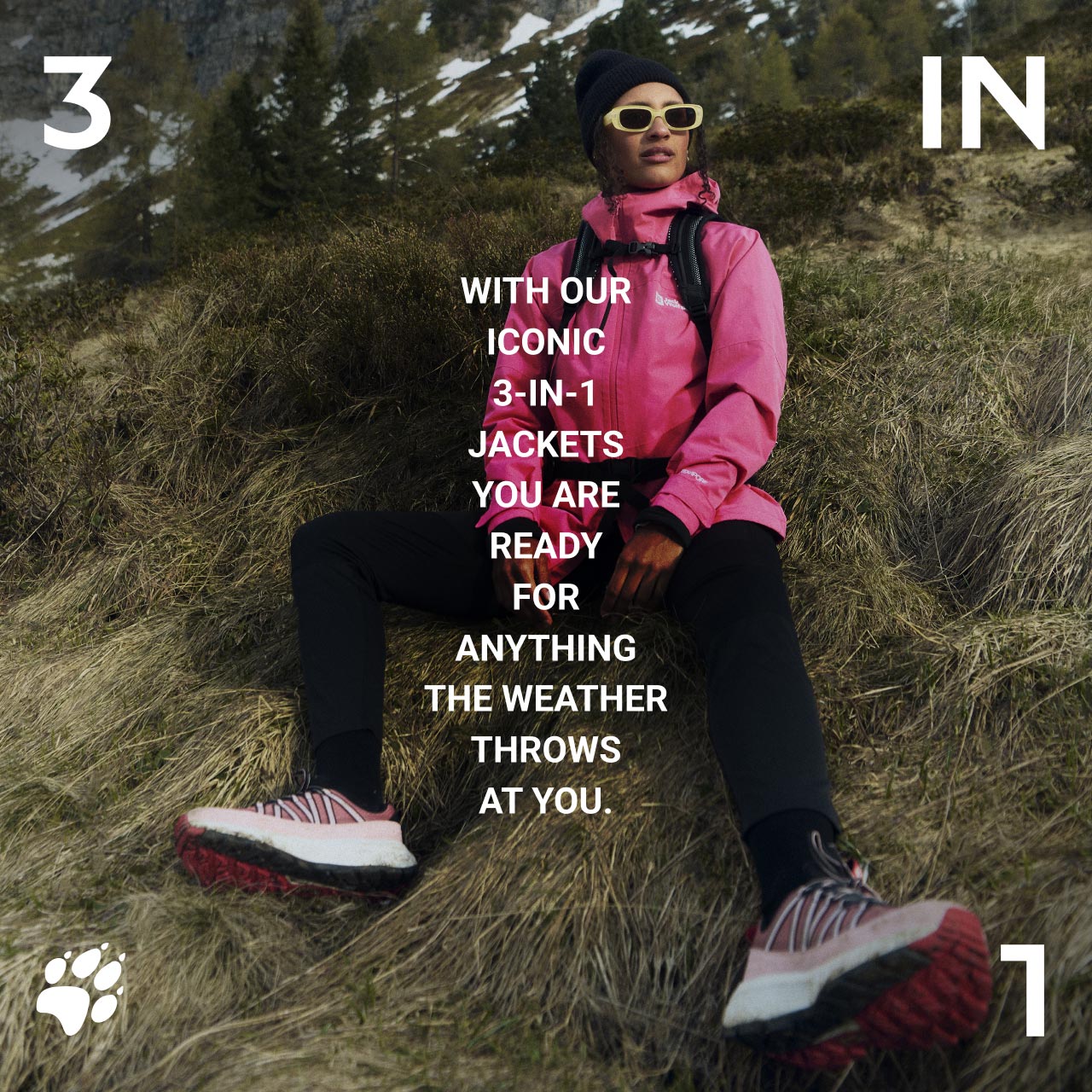 Person in pink jacket and beanie seated on grassy slope, wearing sunglasses and hiking shoes. Text: "With our iconic 3-in-1 jackets, you are ready for anything the weather throws at you."