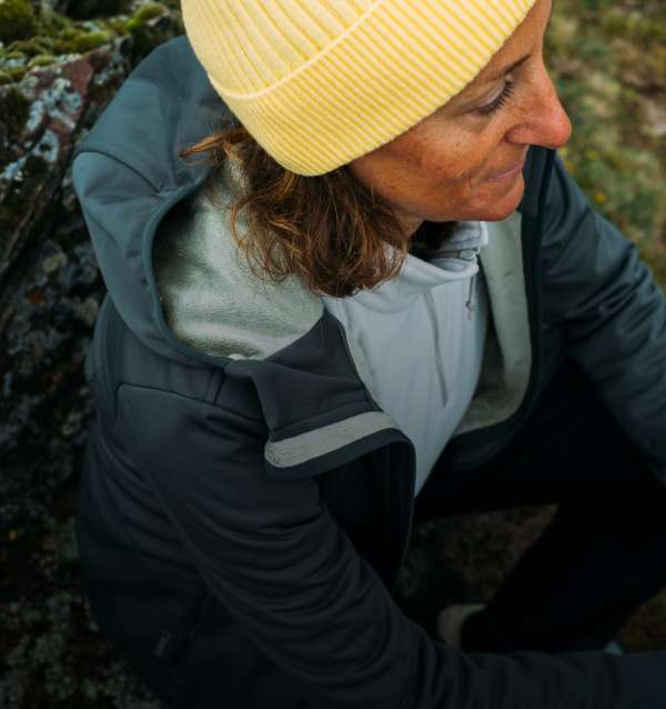 Woman in a fleece and jacket taking a break on a rock