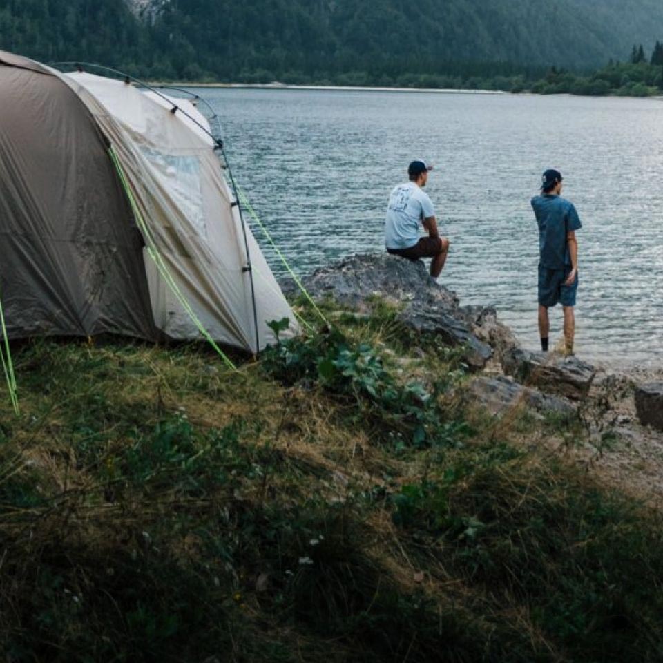 Two people in a tent and forming a heart with their hands